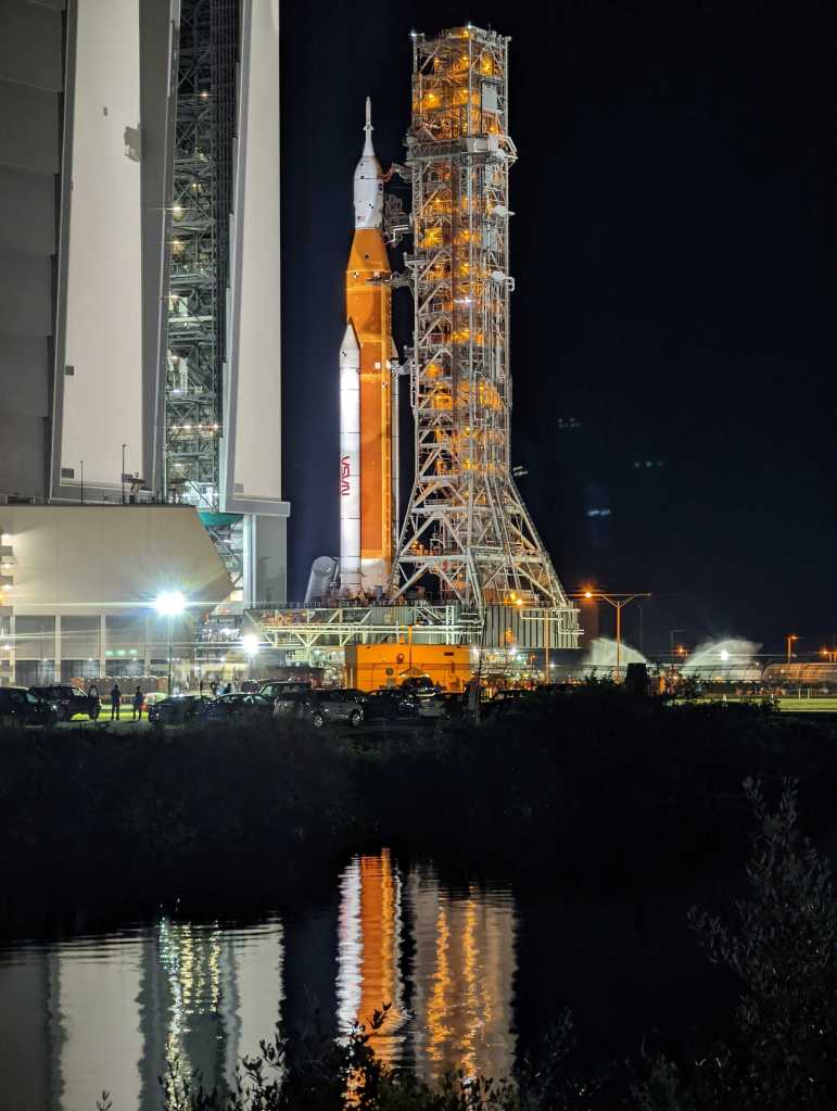SLS reflects in the water at the press site during rollout.